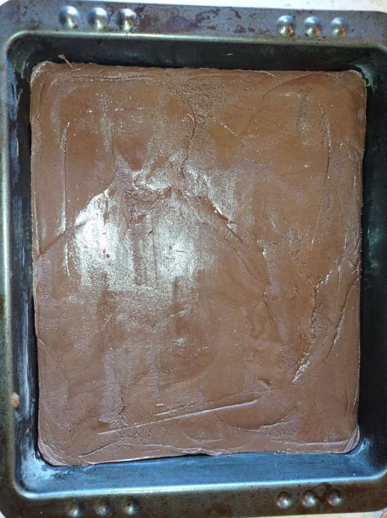 Close-up of melted chocolate spread evenly in a baking tray, ready to set