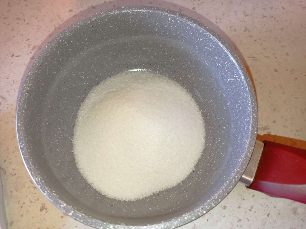 Close-up of sugar placed in a small pot, ready for cooking