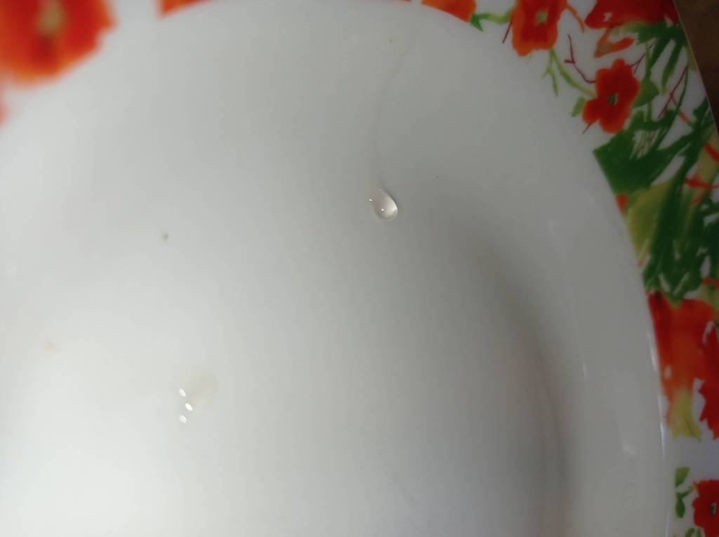 A drop of sugar syrup on a vertically tilted plate, used to check the perfect consistency for homemade chocolate fudge.