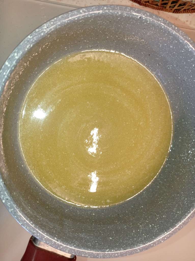 A rich sugar syrup with melted butter added, simmering on the stove for homemade chocolate fudge.