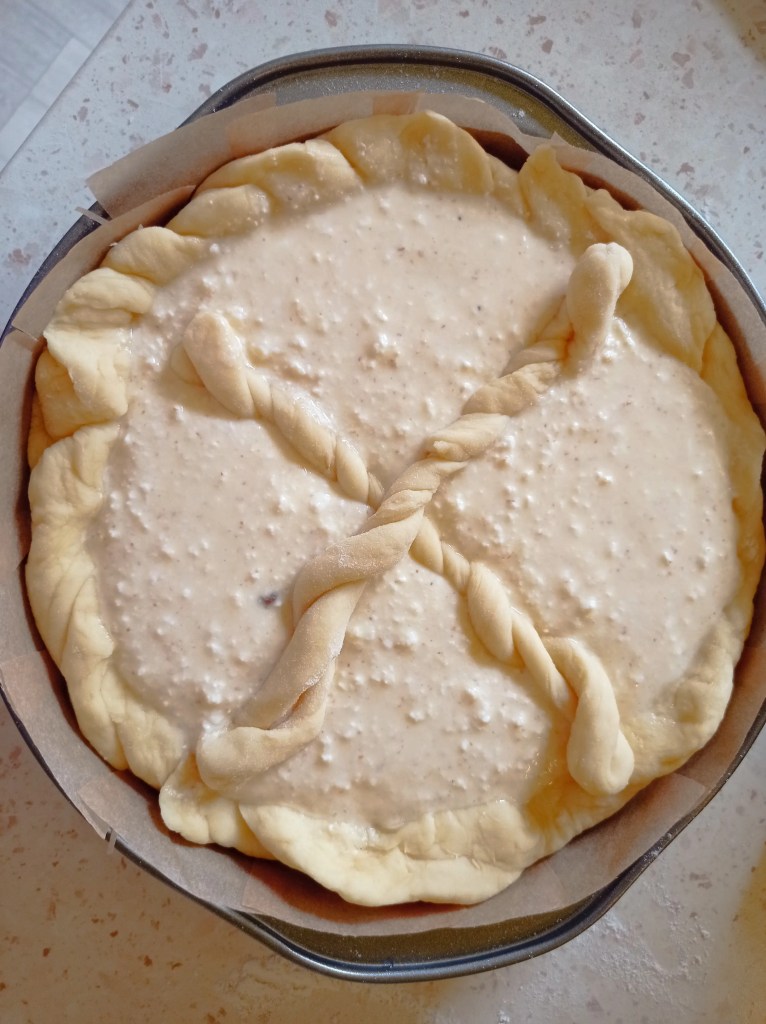 Unbaked traditional Romanian Pasca with cheese filling and twisted dough cross on top.