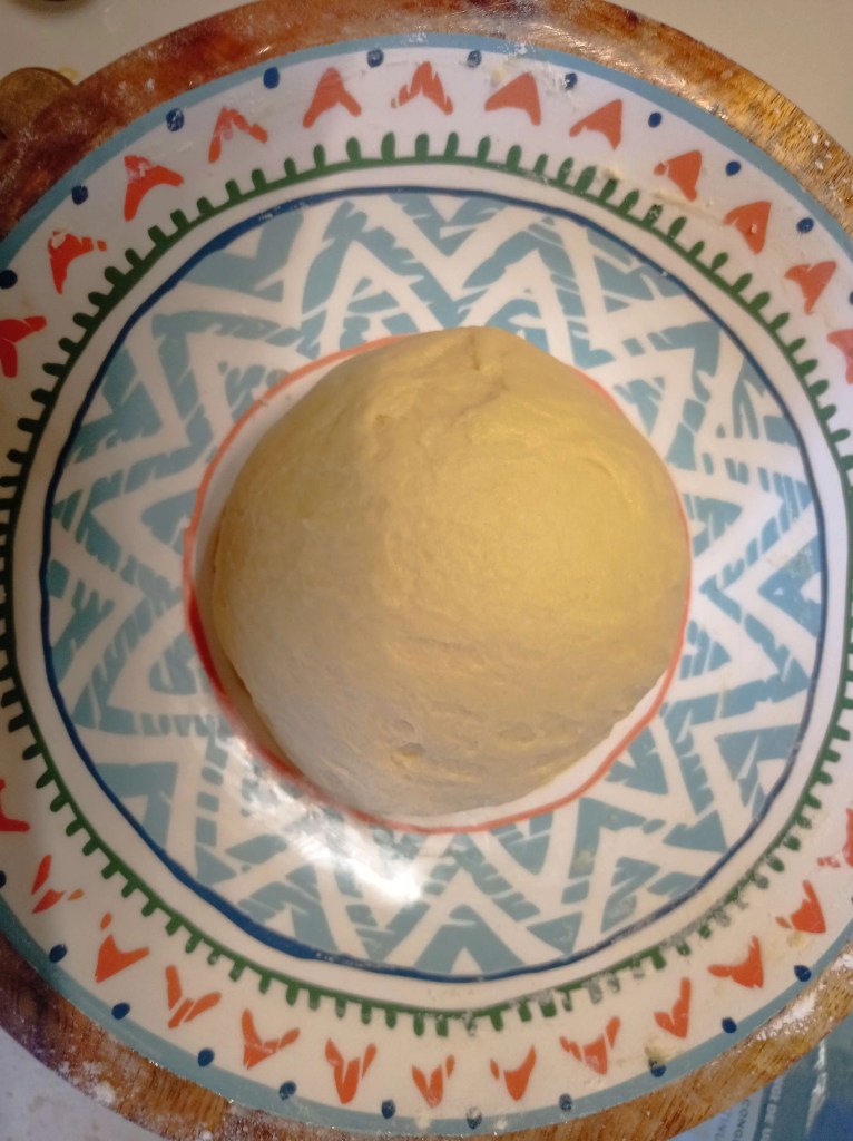 Ball of traditional Pasca dough with milk and butter, placed in a glass bowl before rising