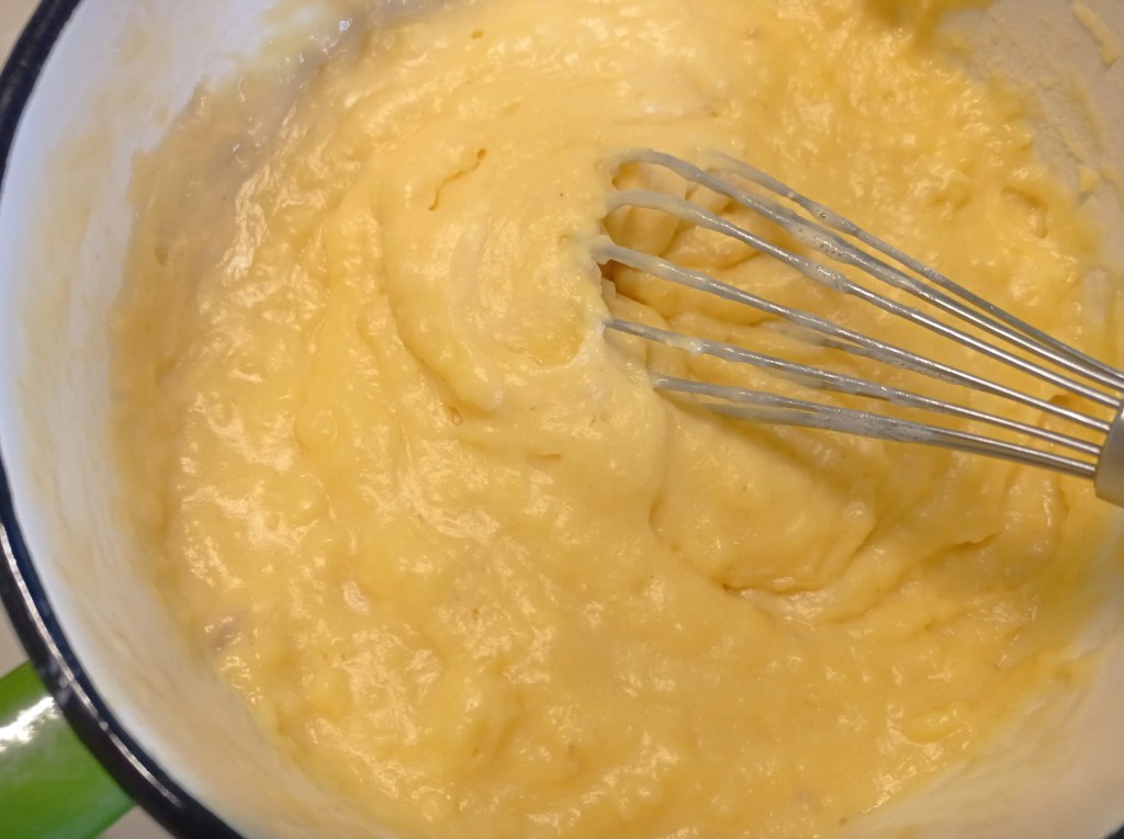 Thick, glossy vanilla custard stirred with a whisk, ready for cooling and Pasca filling