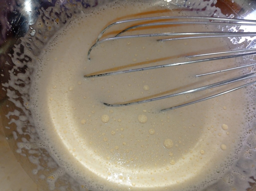 Smooth mixture of whipped egg yolks combined with lactose-free milk and vanilla, ready to be cooked into custard