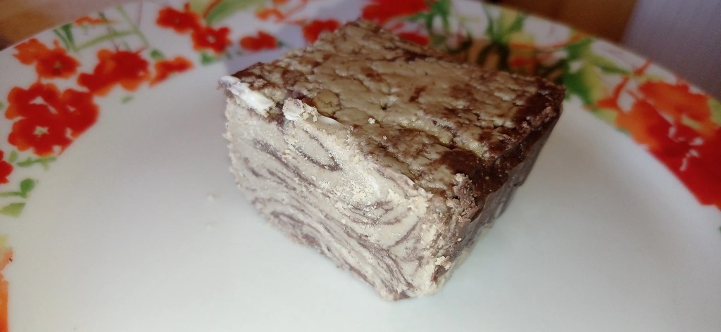 Close-up of a slice of sunflower halva with cocoa swirls on a floral plate
