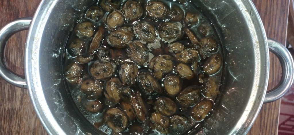 Traditional green walnut preserve in rich syrup, ready to be jarred