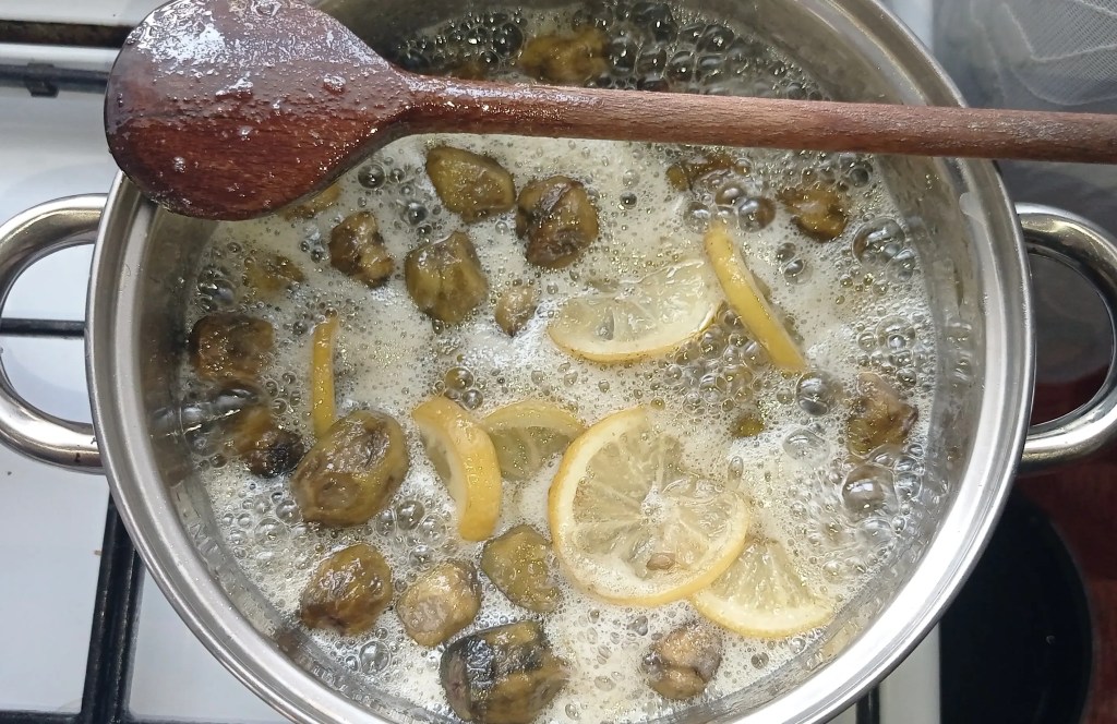 Whole green walnuts and lemon slices boiling in thick sugar syrup