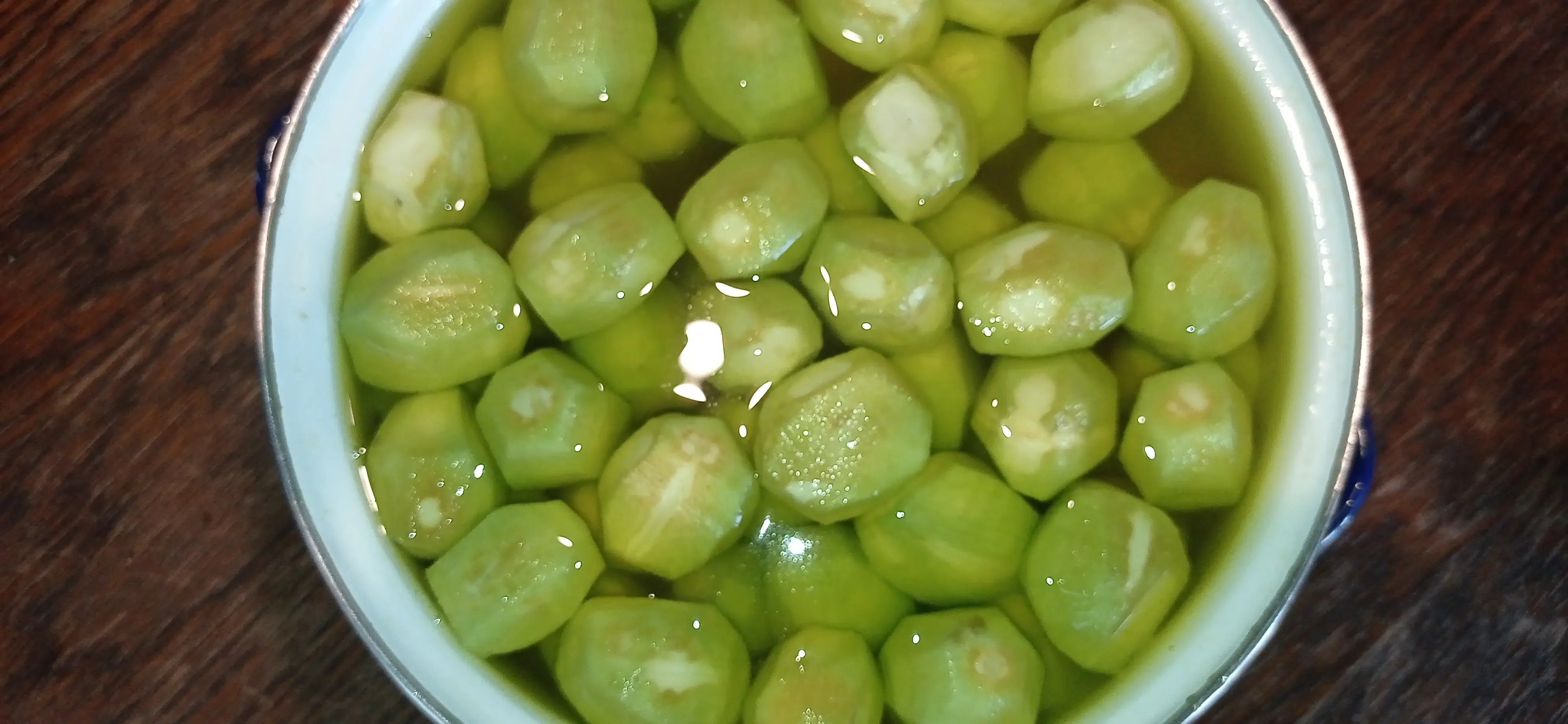 Peeled green walnuts soaking in a pot of water to remove bitterness and dark spots