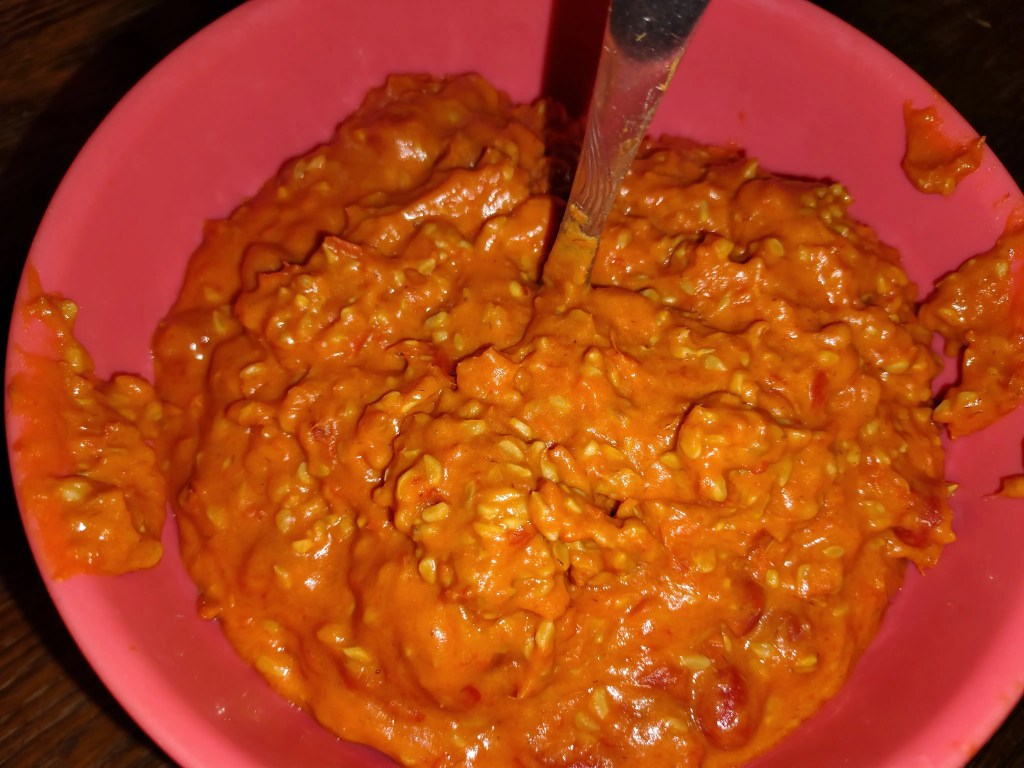 Freshly blended rosehip pulp in a pink bowl, showing the thick, vibrant orange-red texture before straining
