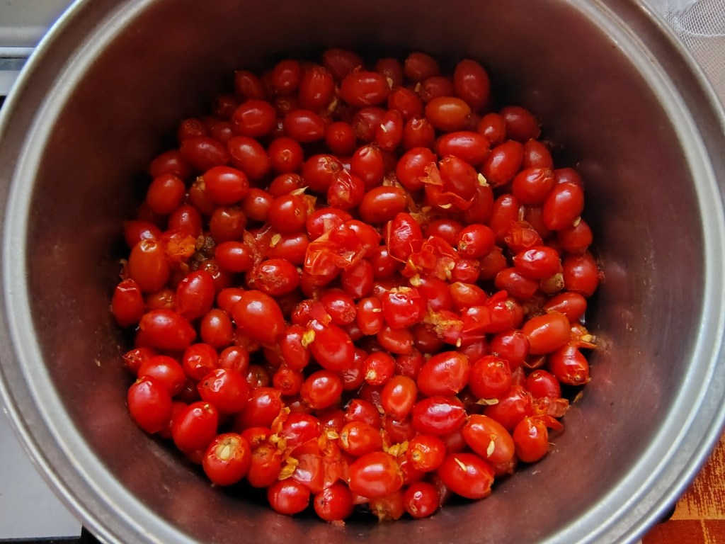 Cooked rosehips in a pot after boiling, visibly softened and ready for mashing or processing.